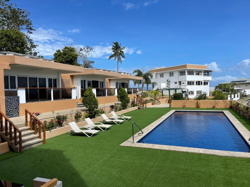 un patio trasero con piscina y sillas y un edificio en Verde View Villas, en Puerto Galera