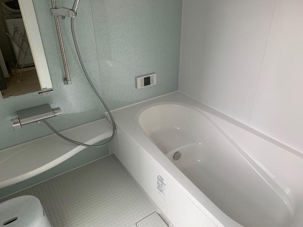 a bathroom with a white tub and a toilet at KAI Ichinomiya in Ichinomiya