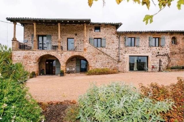 a large brick building with a balcony on it at Au Petit Bonheur chez Bambina in Leynes