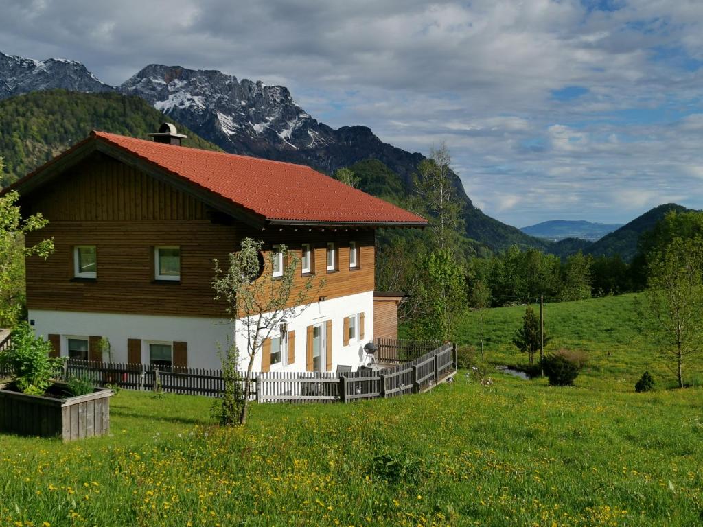 a house in a field with mountains in the background at Ferienwohnung Lohnerlehen in Marktschellenberg