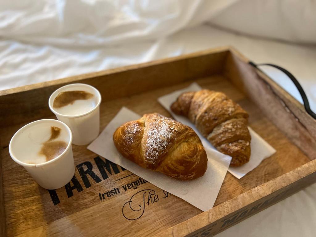 uma bandeja com 2 croissants e 2 chávenas de café em Olympus Luxury Suites em Mola di Bari