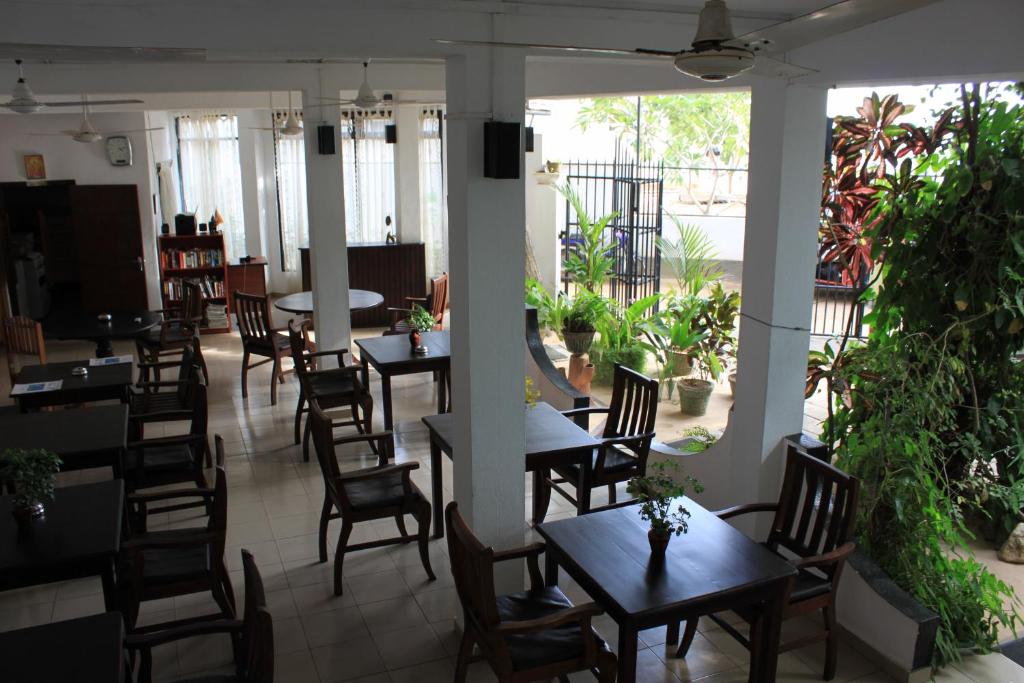 a dining room with tables and chairs and plants at Unawatuna Beach Bungalow - in Unawatuna