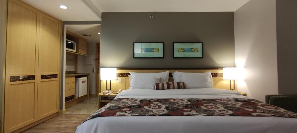 een slaapkamer met een groot bed met twee foto's aan de muur bij RARIDADE!!! - Flat de Alto Padrão - Excelente Atendimento - Ótimo Preço - Cama King Size - Limpeza Diária Gratuita in Brasilia