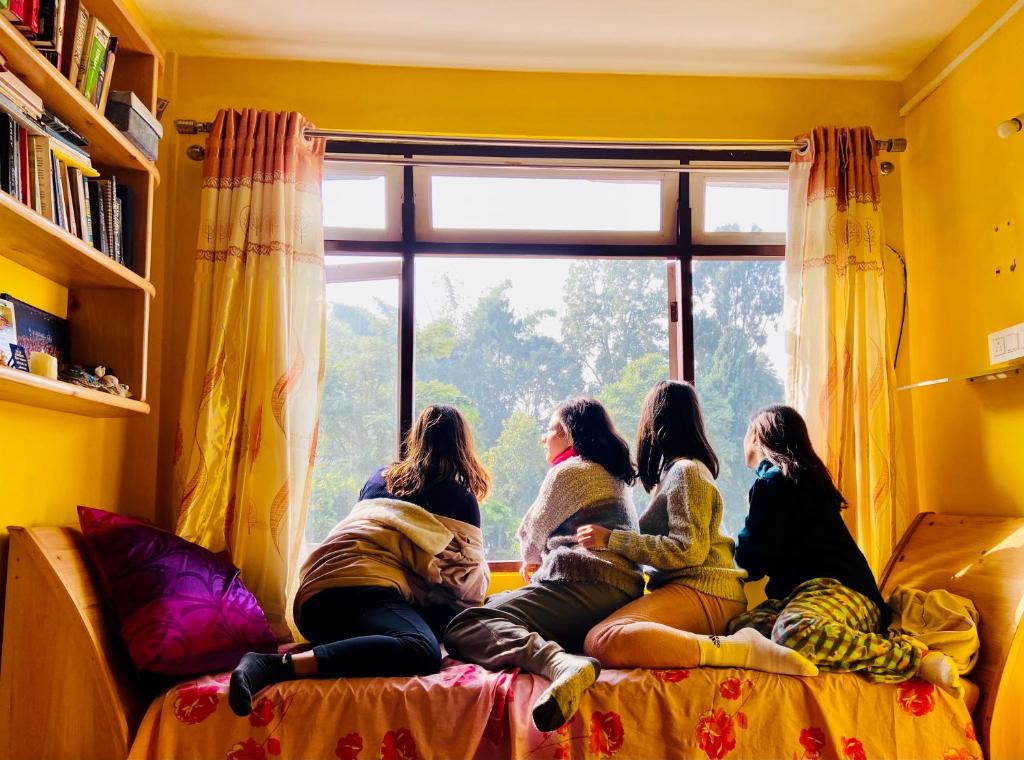 a group of girls sitting on a couch looking out a window at Dew Drop Homestay in Kalimpong