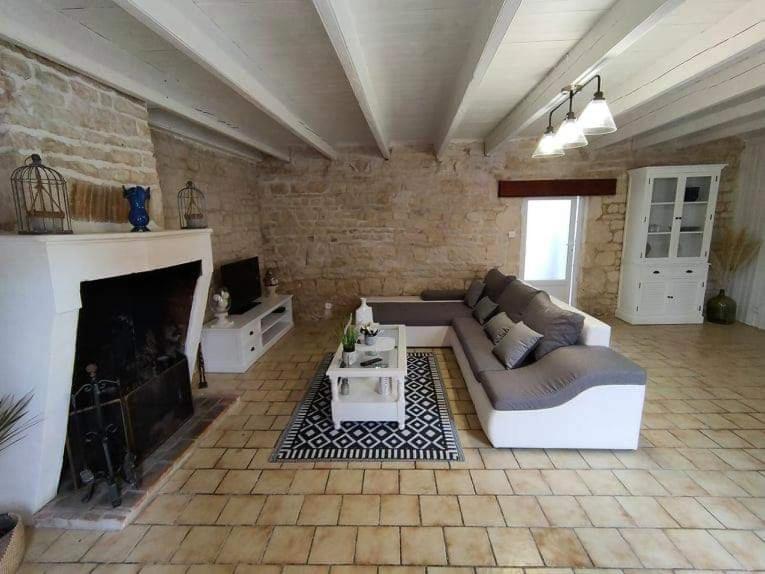 sala de estar con sofá y chimenea en La petite Charentaise, en Saint-Christophe