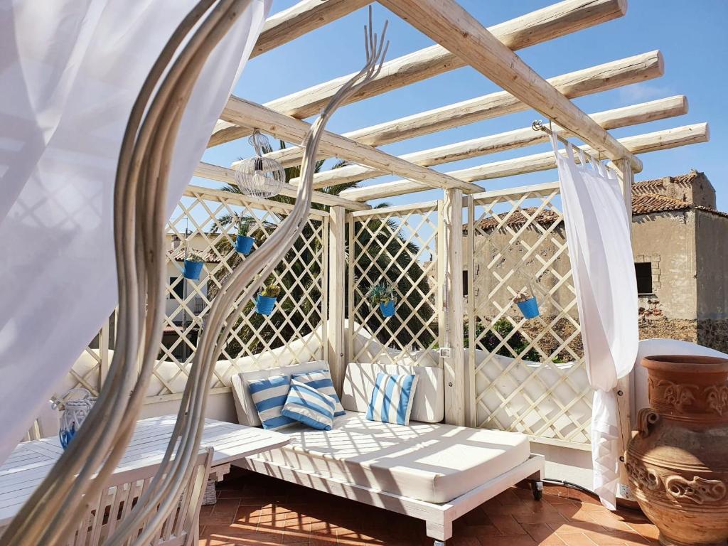 a pergola with a white couch on a patio at Le Andira - Monolocali finemente arredati a pochi passi dal centro storico di Orosei in Orosei