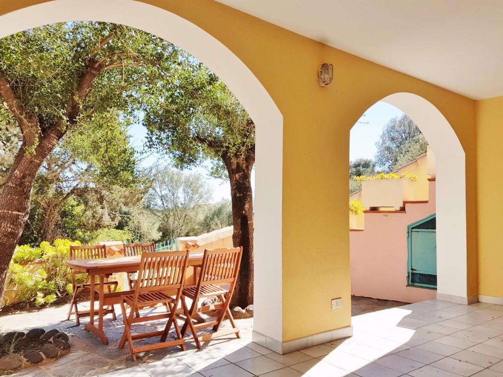un patio con tavolo, sedie e alberi di Dommos - Pintada Apartments a Cala Liberotto