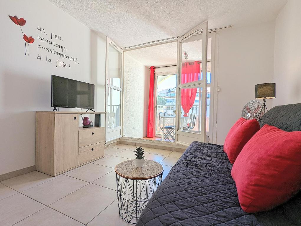 uma sala de estar com um sofá e uma televisão de ecrã plano em Appartement rénové avec parking privatif ,à 2min de la plage em Cap d'Agde