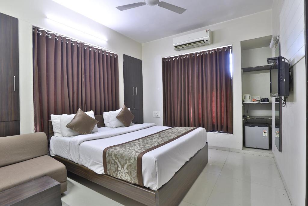 een hotelkamer met een bed en een bank bij Hotel Nova Vatika in Surat