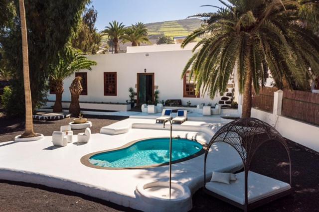 - une piscine dans une cour avec des palmiers dans l'établissement Delmás Hotel Emblemático, à Haría