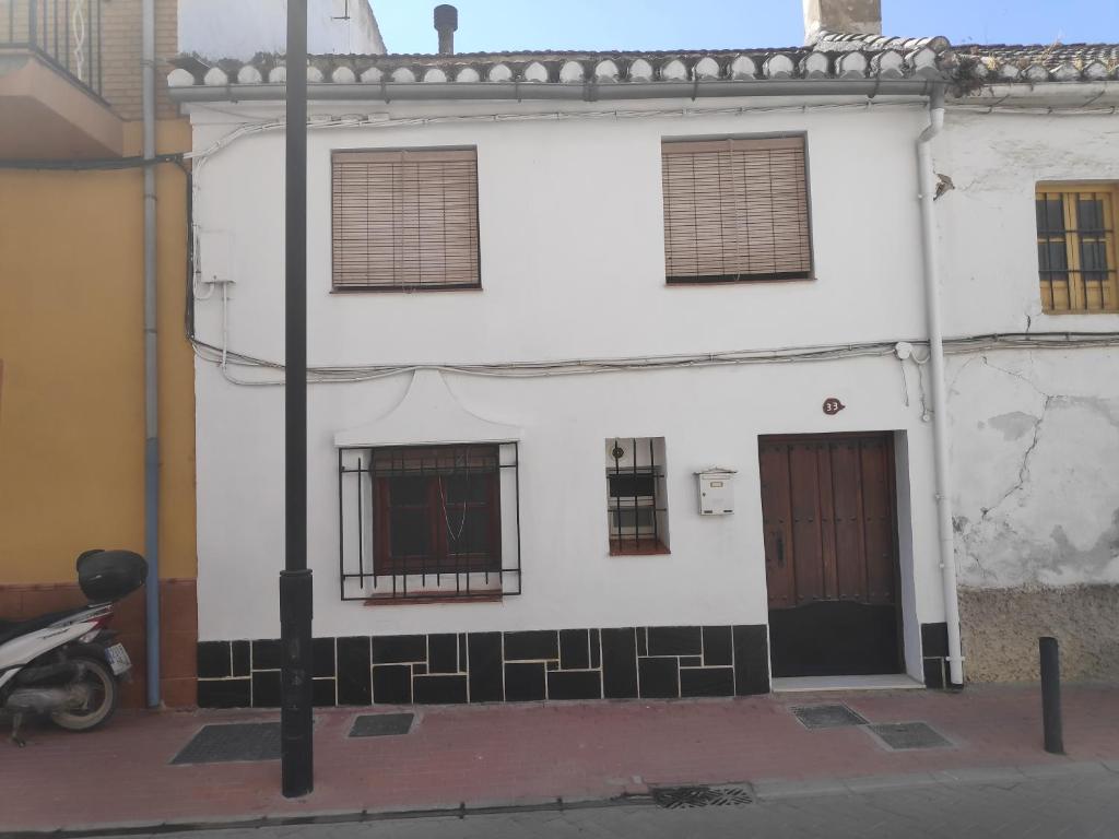 ein weißes Gebäude mit Fenstern und ein Motorrad, das direkt daneben parkt in der Unterkunft Casa en Purchil in Granada