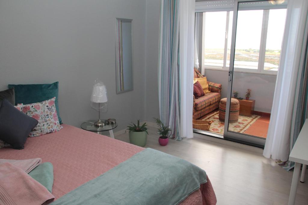 a bedroom with a bed and a balcony with a couch at Ricardo Rolão Vista Mar - Edifício Oásis - Bedrooms in Faro