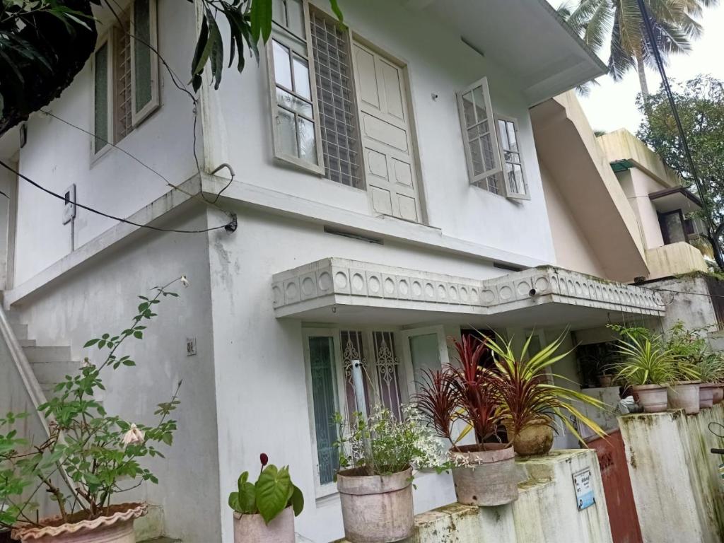 uma casa branca com vasos de plantas em frente em Jestine Homestay em Cochin
