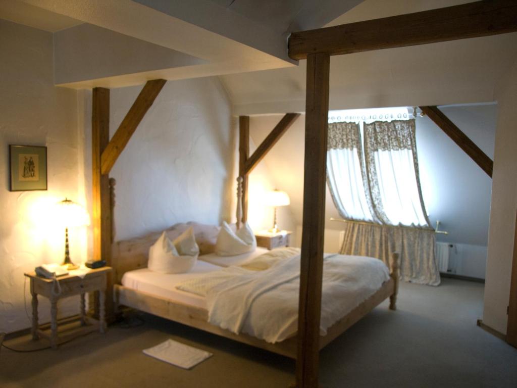 a bedroom with a canopy bed with two windows at Hotel Stadt Hamm in Hamm