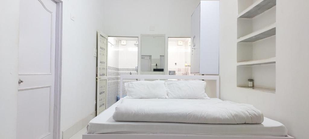 Cette chambre blanche comprend un lit et un miroir. dans l'établissement Planet Star Homestay, à Bikaner