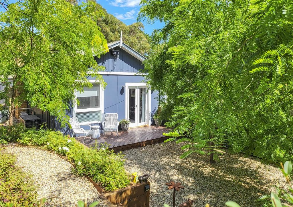 uma casa azul com um deque de madeira num quintal em Locarno Cottage em Hepburn Springs