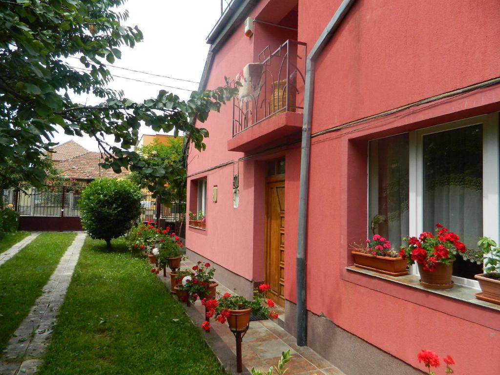un edificio rosa con flores a un lado. en Cazare Vio, en Cluj-Napoca