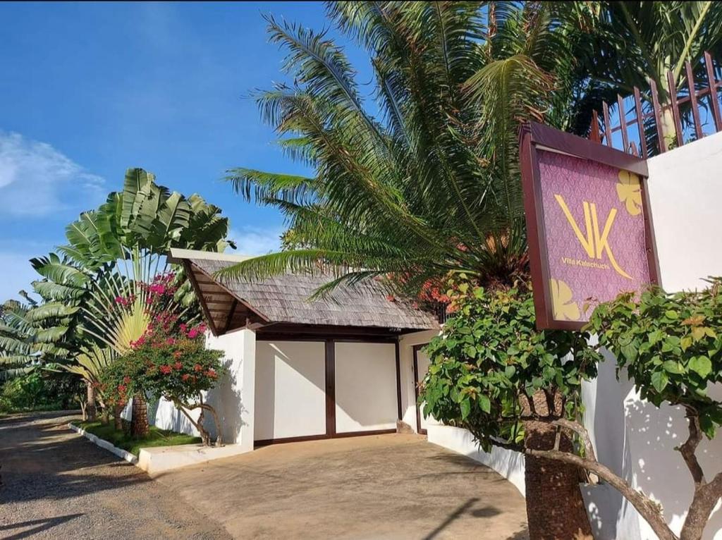 ein Schild an der Seite eines Gebäudes mit einer Palme in der Unterkunft Villa Kalachuchi V.K in Puerto Princesa