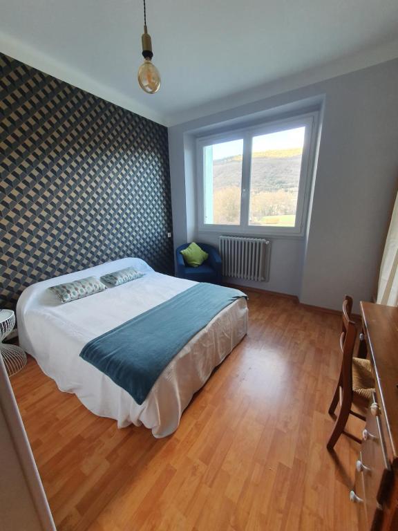 1 dormitorio con cama, escritorio y ventana en Chambre privée du Majestic en Saint-Affrique