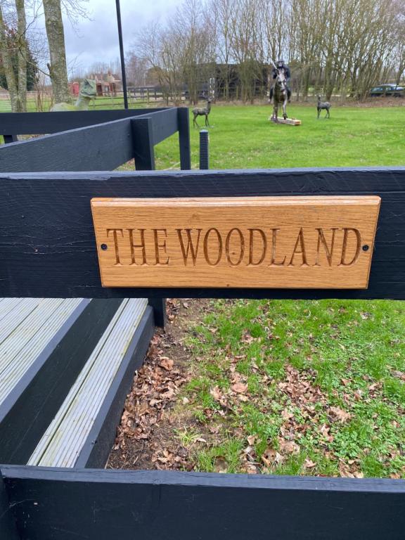 een bord op een parkbank dat het bos leest bij The Woodland in Wyboston