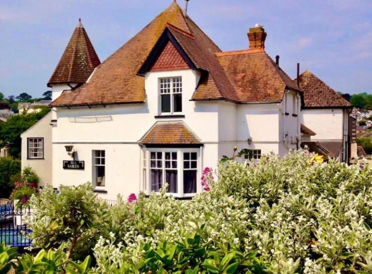 a white house with a brown roof and some bushes at Quirky Lyme Regis Apartment Near Beach in Lyme Regis