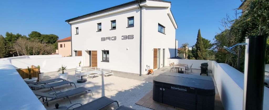a white building with chairs and a grill on a patio at Villa Brig 36 in Premantura