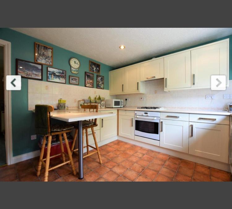 een keuken met witte kasten en een tafel met stoelen bij Beautiful double en-suite room in Oakham