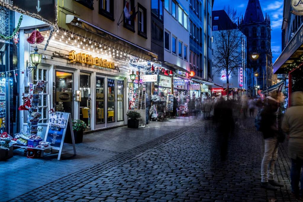 een stadsstraat 's nachts met mensen die over straat lopen bij Hotel am Museum Köln in Keulen