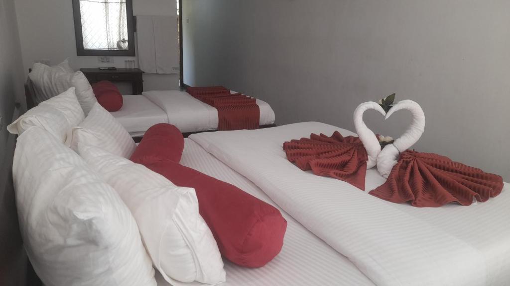 ハプタレーにあるDiscovery Retreat Blackwoodの白と赤の毛布と白の白鳥が敷かれたベッド3台