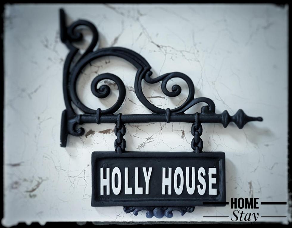 Un cartello di Holly House appeso a un muro di Holly House Homestay a Ella