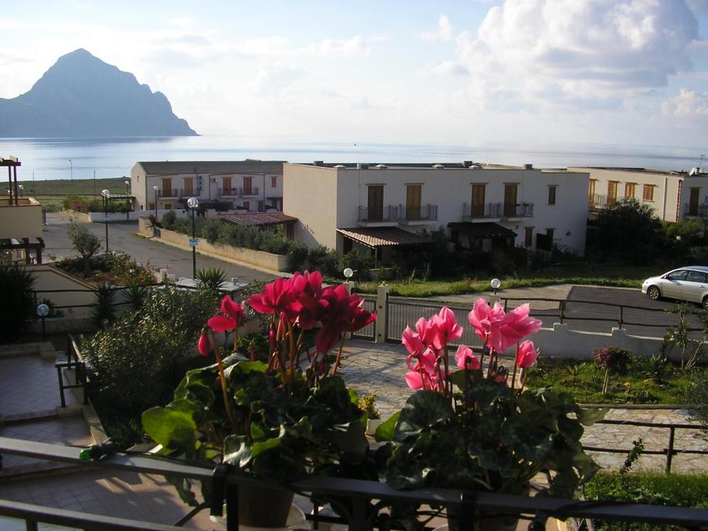 a view from a balcony with pink flowers and a mountain at Baglio Makari in San Vito lo Capo