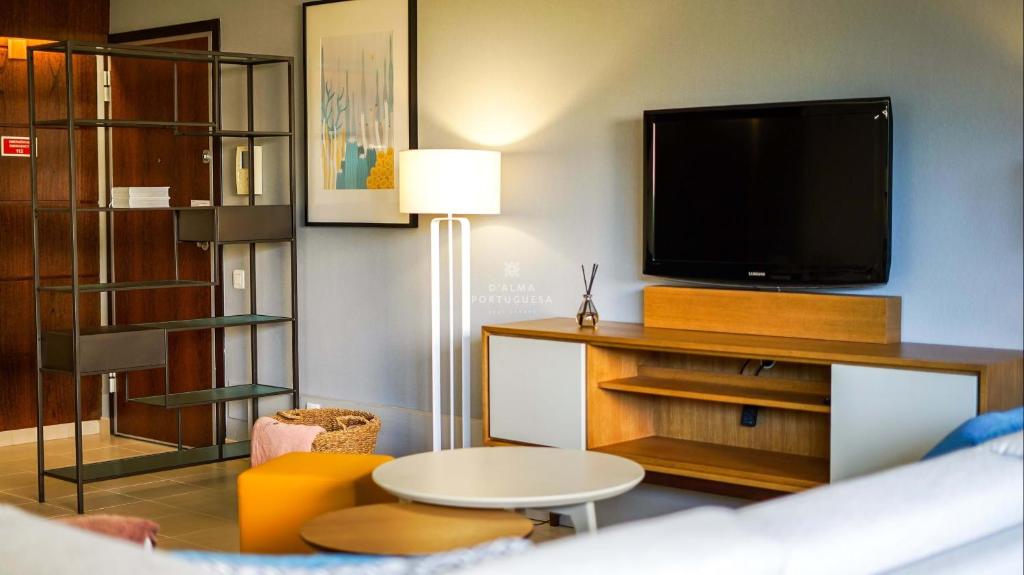 een woonkamer met een flatscreen-tv en een tafel bij Coco Design Apartment Salgados Beach - By Dalma Portuguesa in Galé