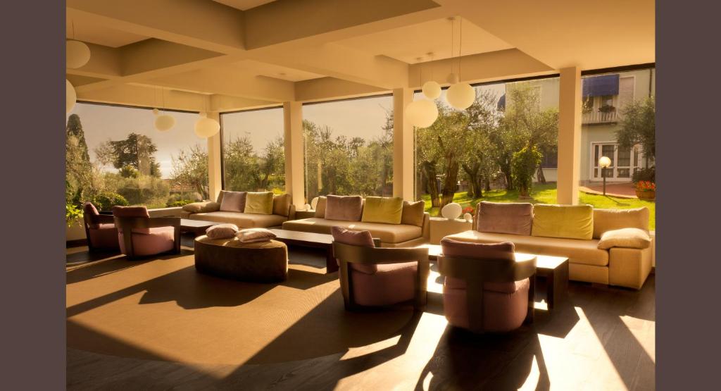 - un salon avec des canapés, des chaises et des fenêtres dans l'établissement Hotel Désirée - Garda Lake Collection, à Sirmione
