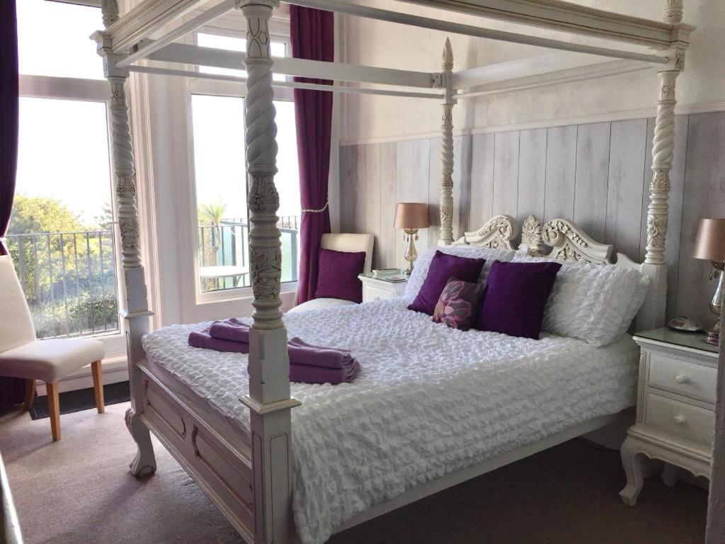 a bedroom with a canopy bed with purple pillows at Seaview Sanctuary in Eastbourne