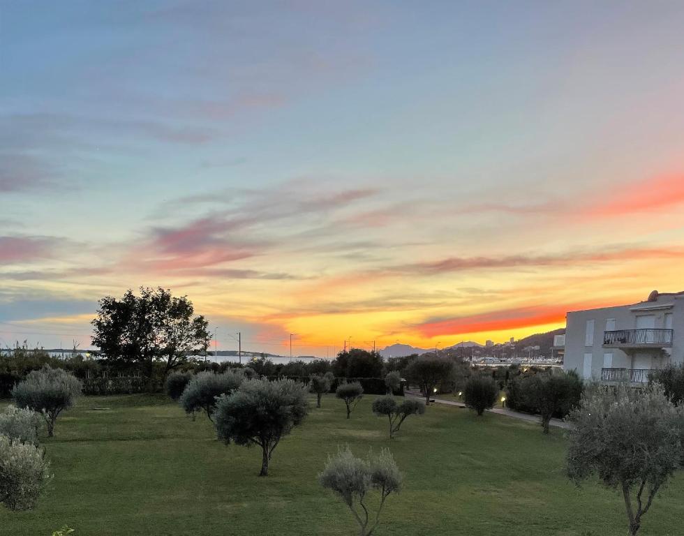 um pôr-do-sol sobre um campo com árvores num parque em Feels like home JUAN FLORE - Air-conditioned furnished apartment with terrace & parking em Antibes