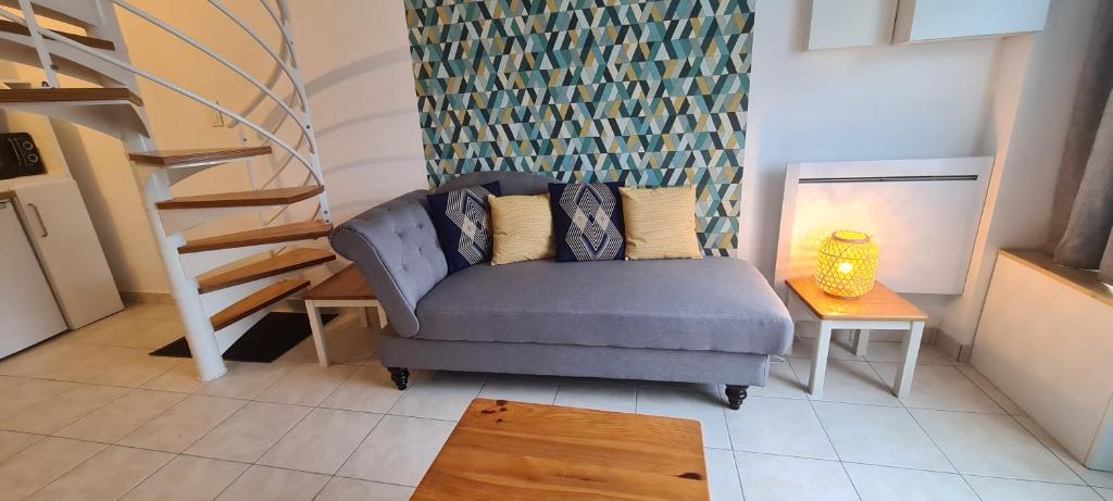 ein Wohnzimmer mit einem blauen Sofa und einer Treppe in der Unterkunft Appartement Samuel centre ville Les Herbiers, 10 min du Puy du Fou in Les Herbiers