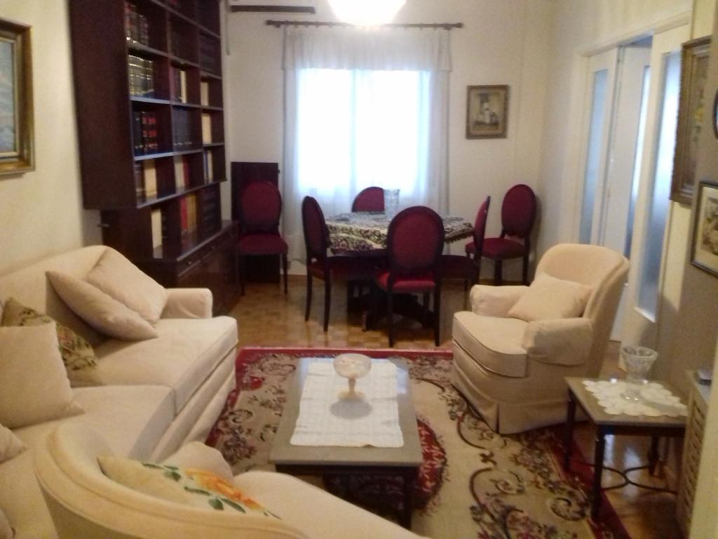 a living room with white couches and a table and chairs at George appartment in Athens