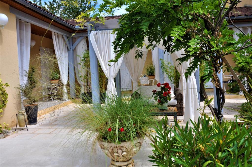 a patio with white drapes and plants at Les Pigeonnes in Groléjac