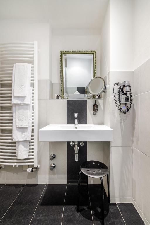 a bathroom with a sink and a stool under a mirror at Bohemian Hotel in Regensburg