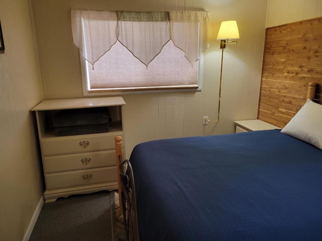 a bedroom with a blue bed and a window at Husker Inn in North Platte