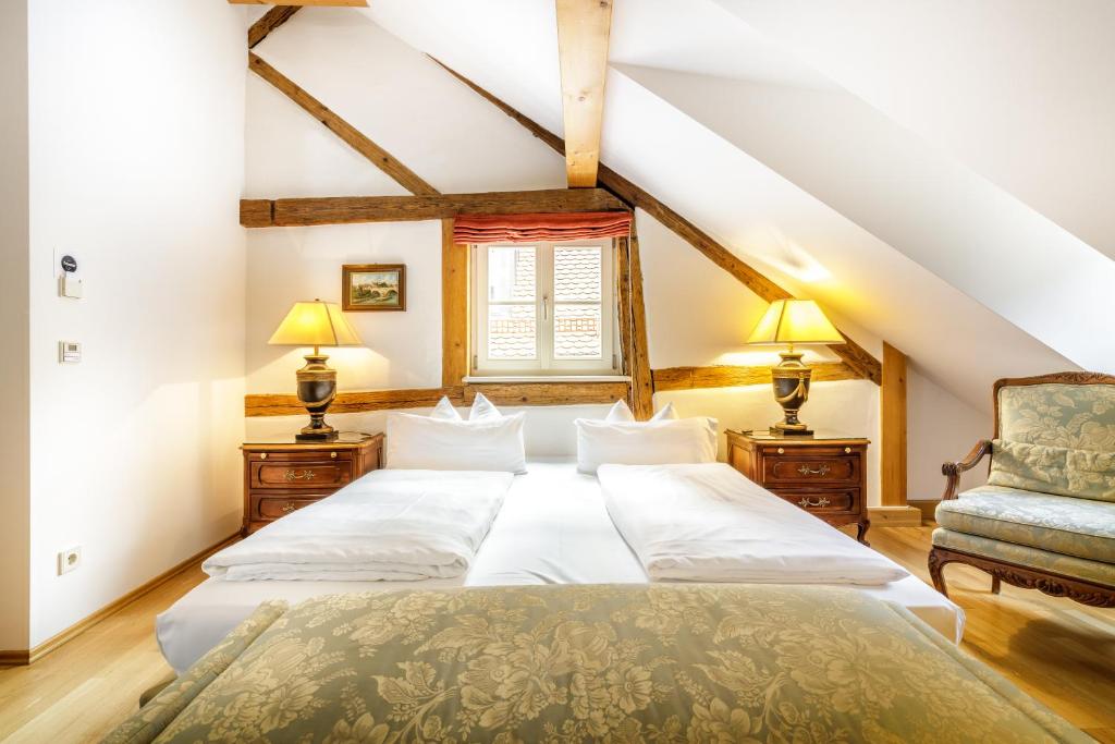 a attic bedroom with a bed and a chair at Bohemian Hotel in Regensburg