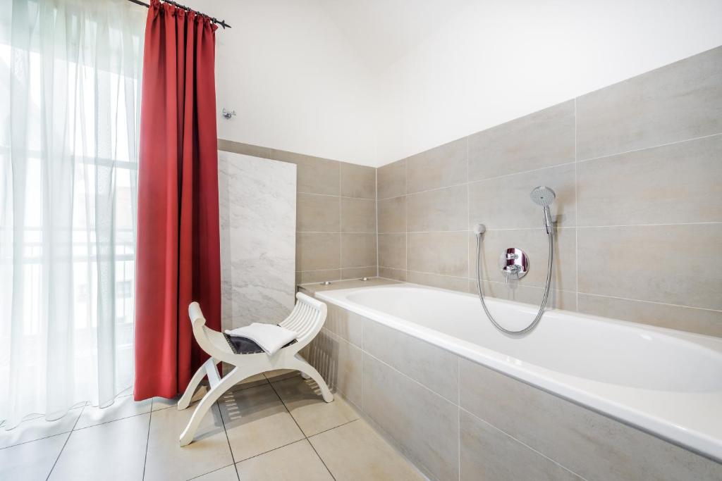 a bathroom with a tub and a chair and a shower at Bohemian Hotel in Regensburg
