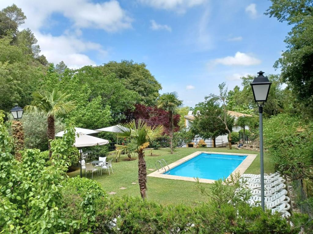 a swimming pool in a garden with a table and chairs at Casa Fuente de Rechita in La Iruela