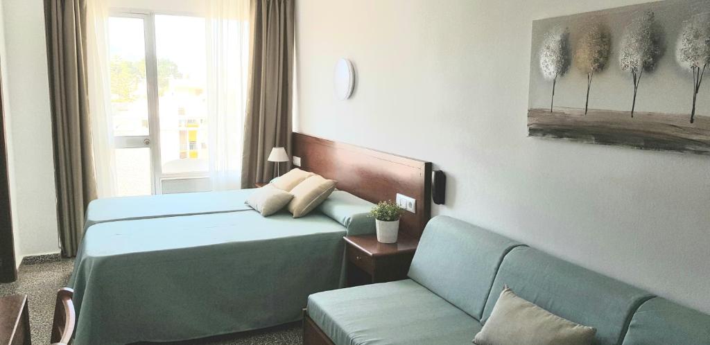 pokój hotelowy z 2 łóżkami i kanapą w obiekcie Hotel Sur w mieście Cala Bona