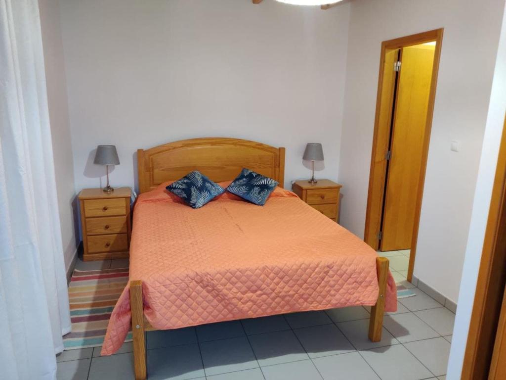 a bedroom with a bed with two blue pillows on it at Casa da Isabel in São Roque do Pico