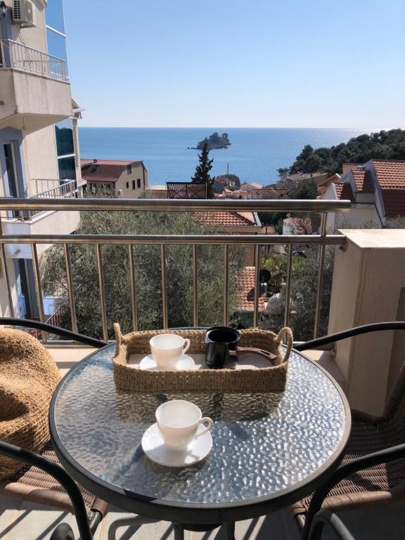 a table with two cups and a basket on a balcony at Petrovac Holiday Apartments 2 in Petrovac na Moru
