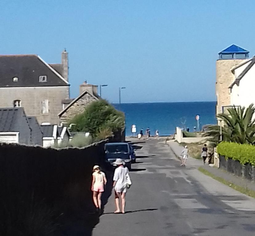 zwei Menschen, die eine Straße entlang gehen, neben dem Meer in der Unterkunft Appartement cosy 100m plage de Pentrez in Saint-Nic