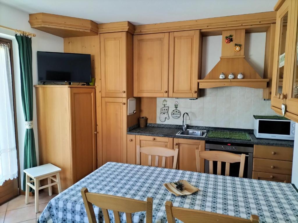 una cocina con armarios de madera y una mesa con sillas. en Baita Rutic, en Oga