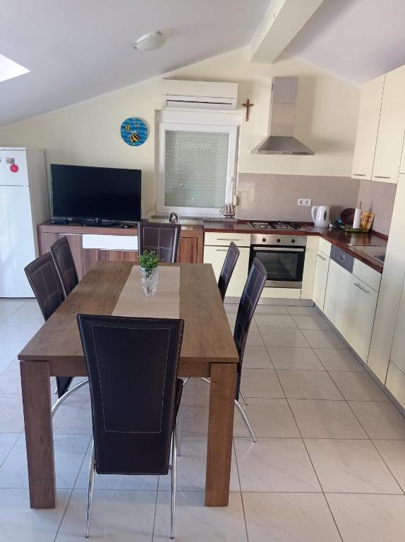 a kitchen with a wooden table and black chairs at Apartman Mia Mare in Kraj