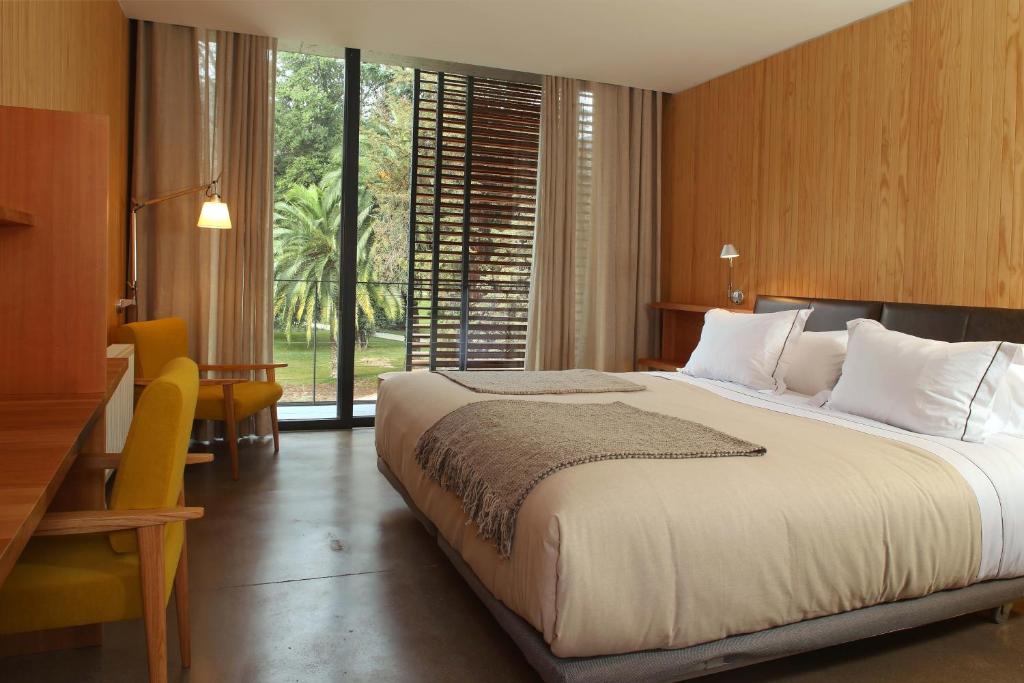 a bedroom with a large bed with a large window at Las Majadas Hotel & Centro de Reuniones in Pirque
